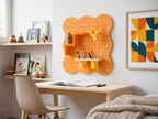 Pegboard Curves orange pastel au-dessus d'un bureau d'enfant avec étagère escalier, patère main et pot à crayons double