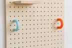Anneaux colorés bleu ciel et orange sur un pegboard en bouleau