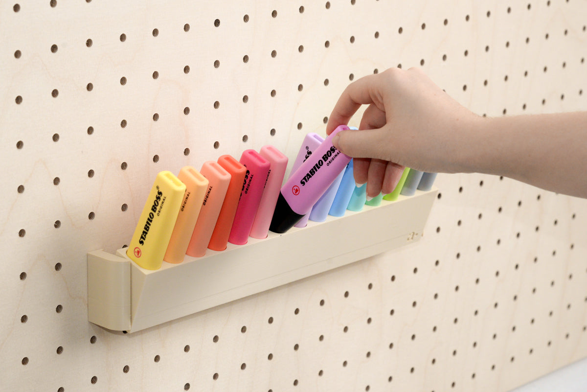 Hand nimmt einen Pastell-Textmarker aus dem kippbaren Pegboard-Halter - Aire