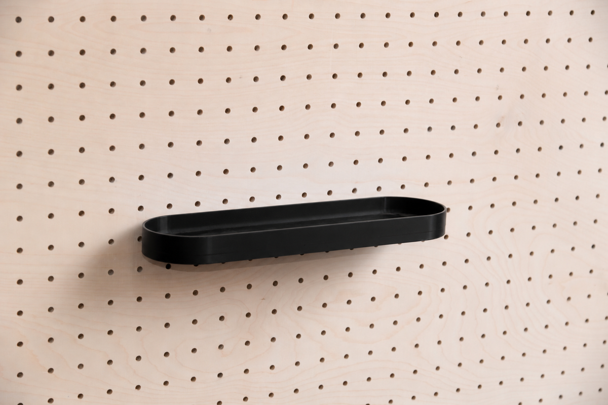Abgerundetes Regalbrett mit Kanten in Schwarz mittig an einem Birken-Pegboard, Frontansicht