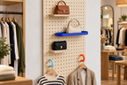 Présentoir pegboard en boutique avec anneaux colorés pour cintres et sacs à main