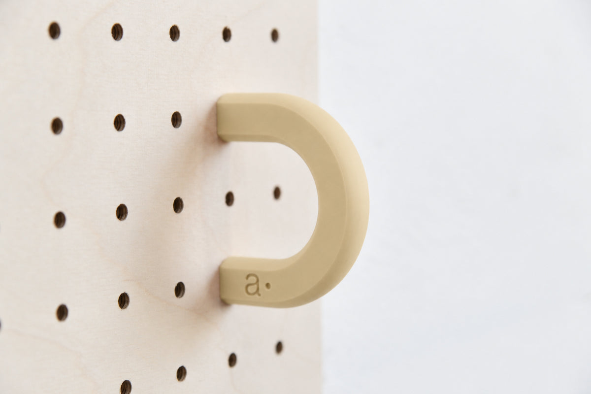 Anilla de color beige talla M en un pegboard de abedul