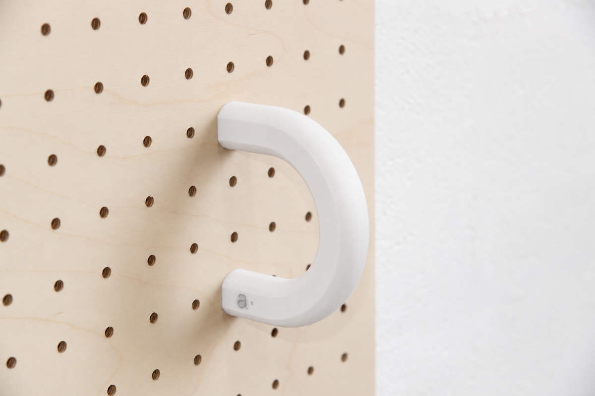 Anilla de color blanco talla L en un pegboard de abedul