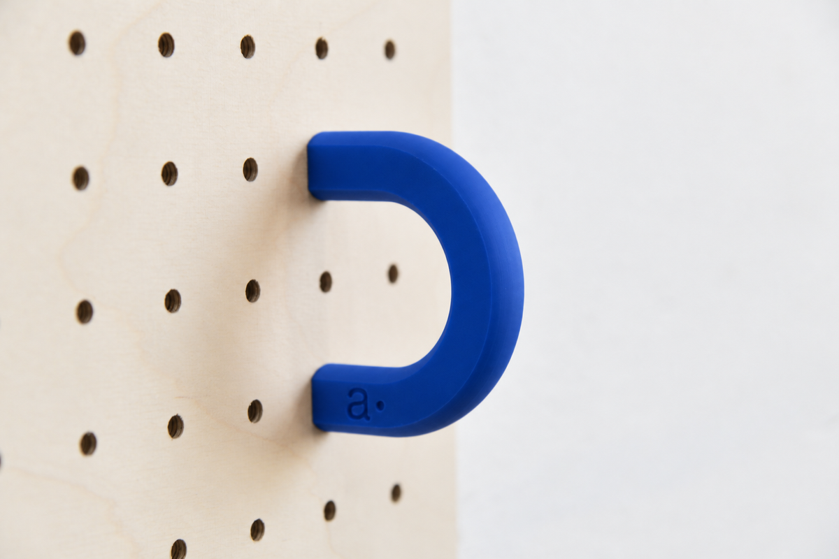 Anilla de color azul talla M en un pegboard de abedul