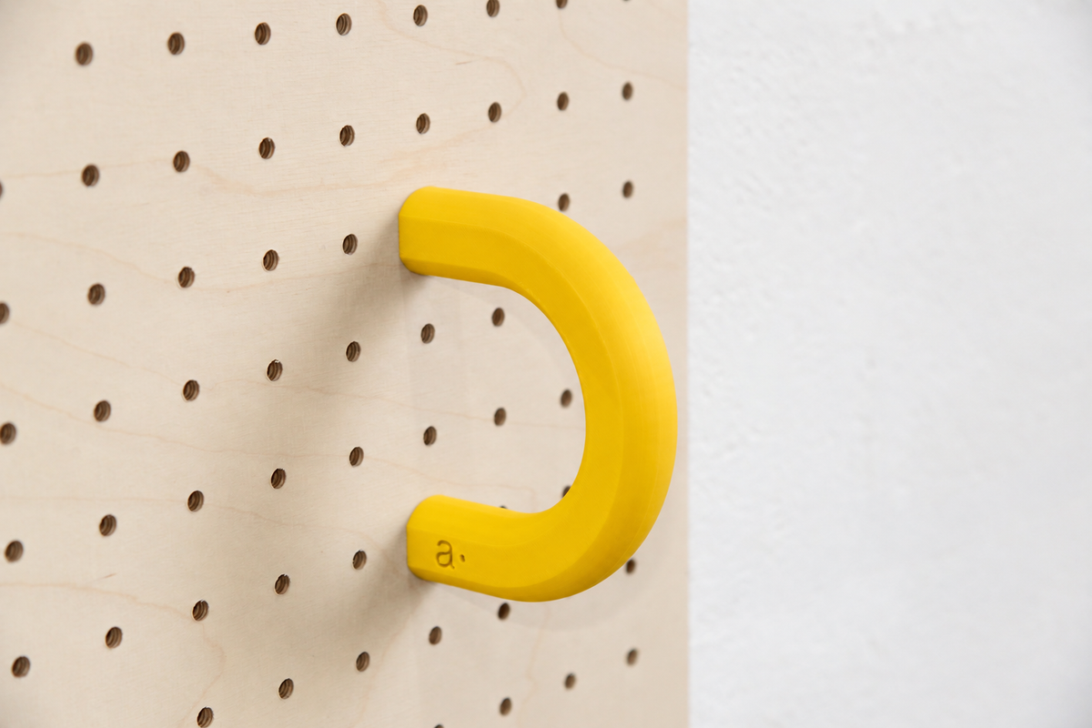 Anilla de color amarillo talla L en un pegboard de abedul