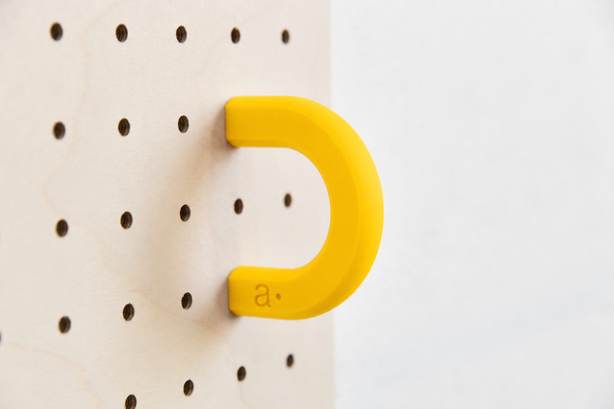 Anilla de color amarillo talla M en un pegboard de abedul