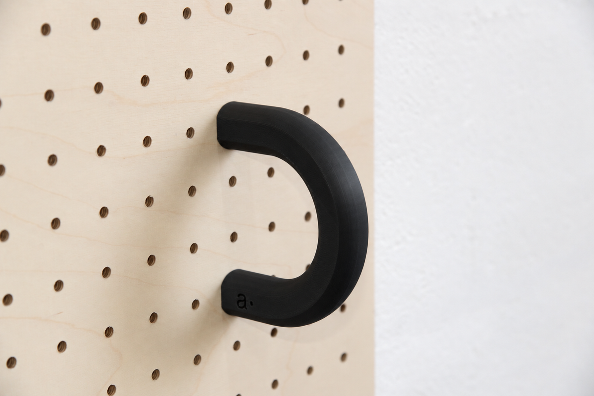 Anilla de color negro talla L en un pegboard de abedul
