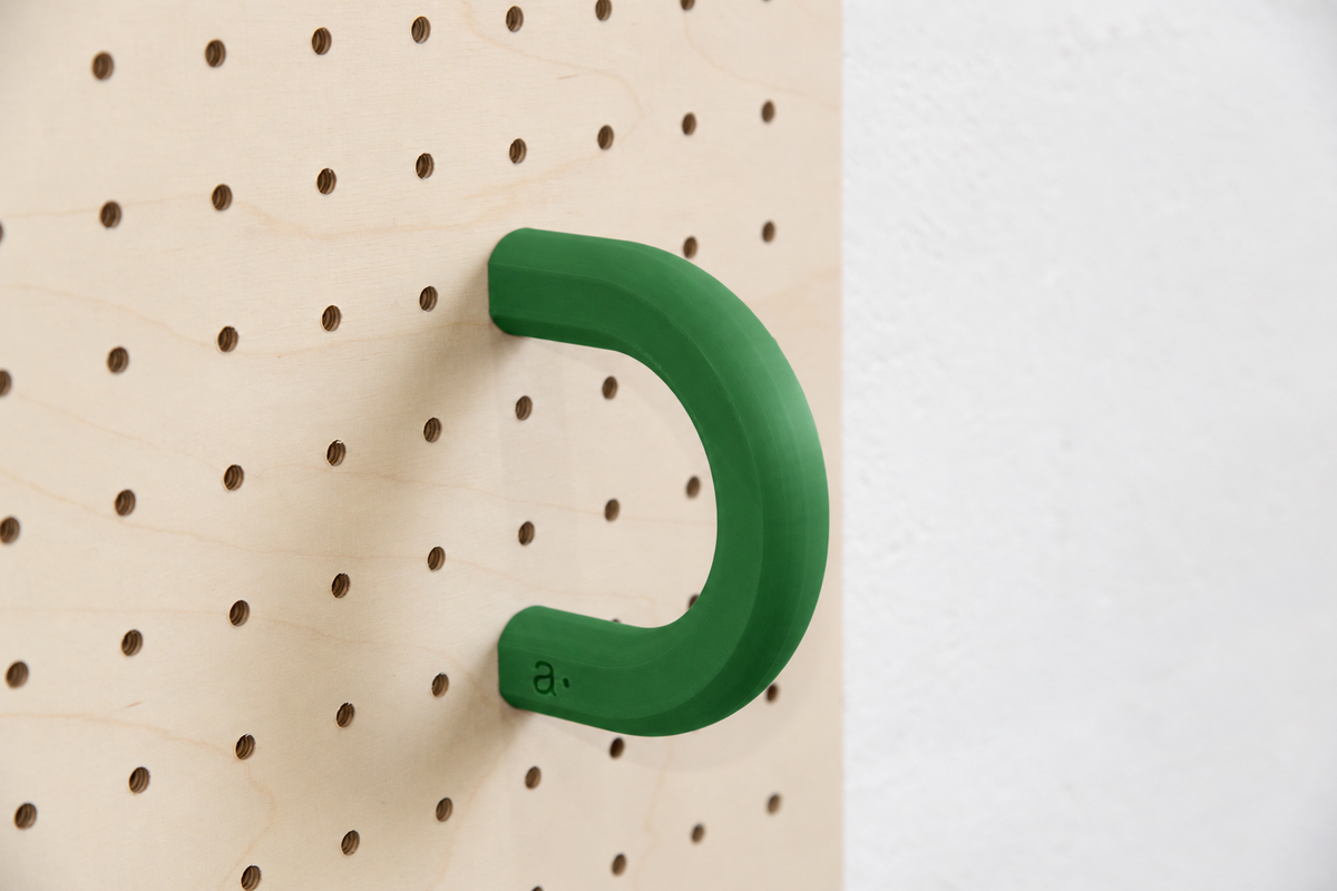 Anilla de color verde talla L en un pegboard de abedul
