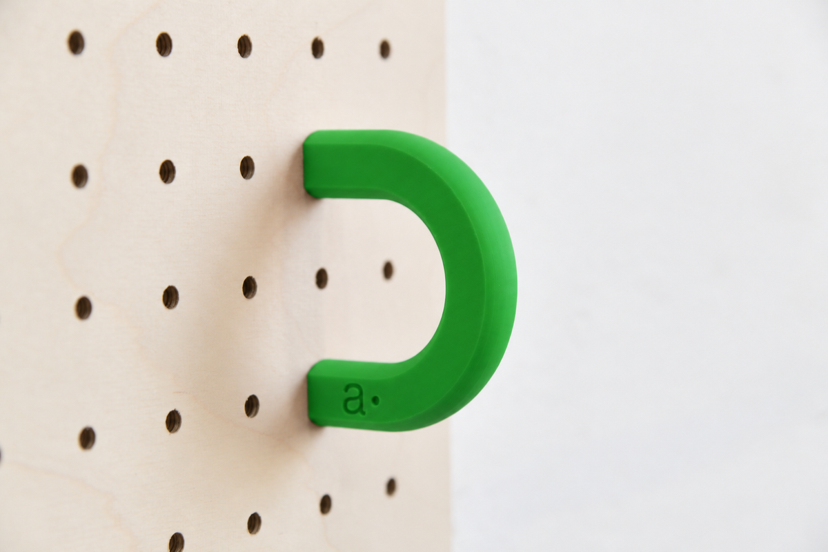 Anilla de color verde talla M en un pegboard de abedul