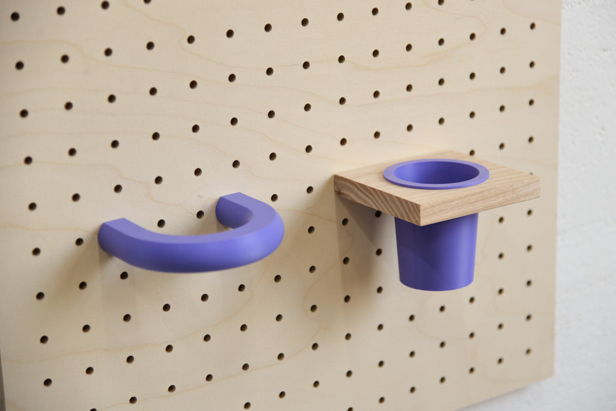 Violetter Ring an einem Pegboard aus Birke, neben einem violetten Hängetopf