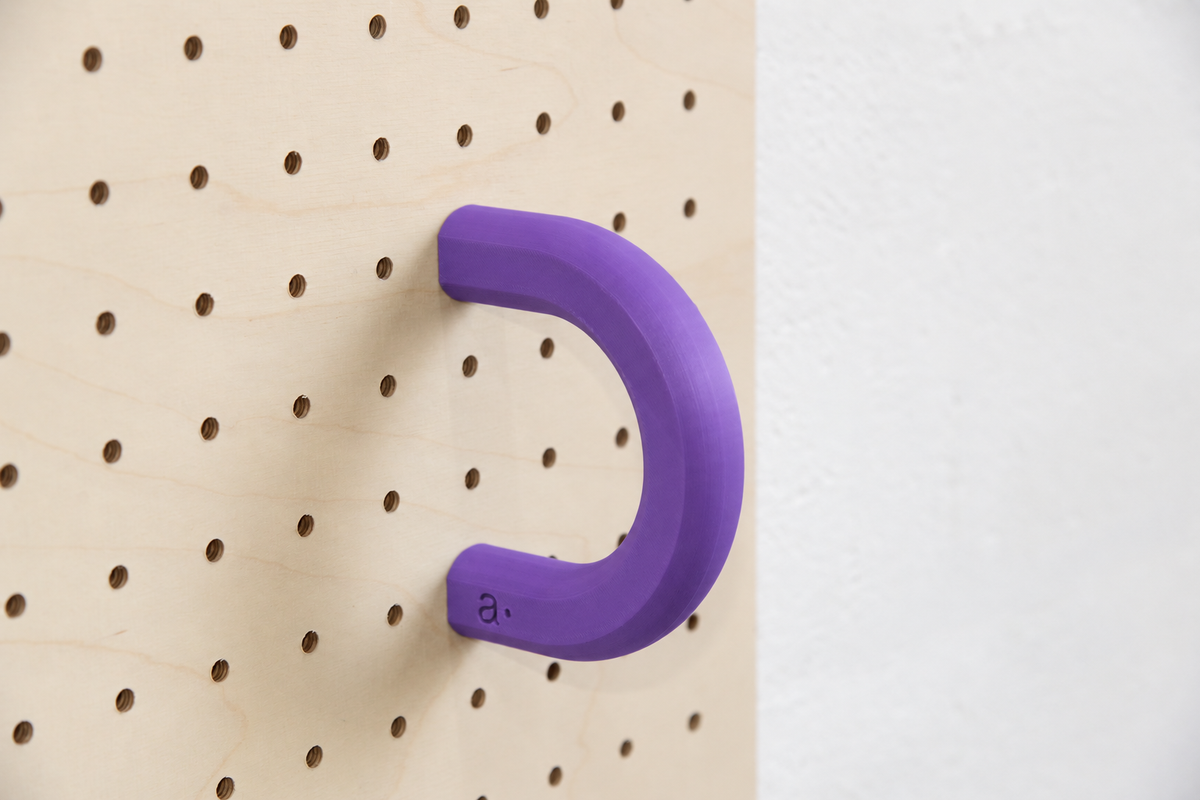 Anilla de color violeta talla L en un pegboard de abedul