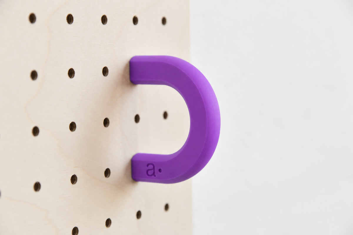 Anilla de color violeta talla M en un pegboard de abedul
