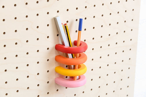Anneaux colorés empilés en pot à crayons sur pegboard en bouleau