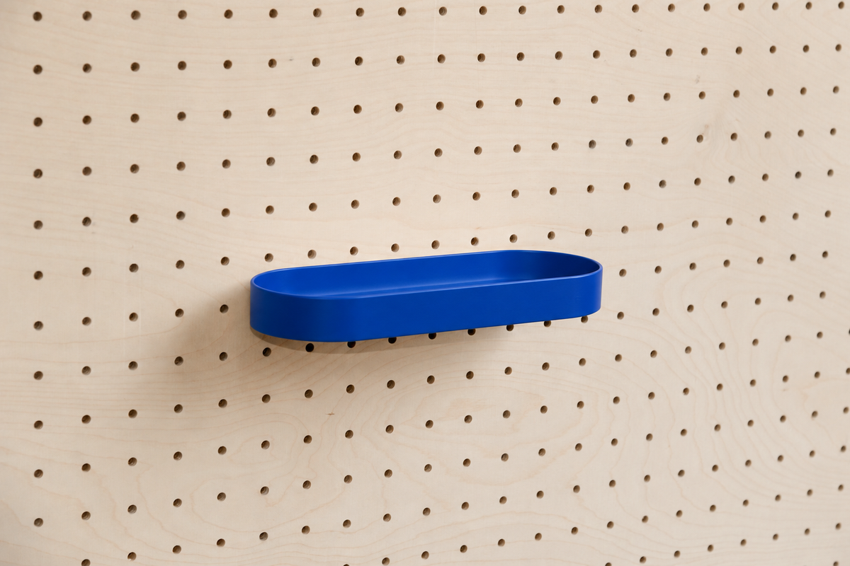 Abgerundetes Regalbrett mit Kanten in Blau an einem Birken-Pegboard, leicht schräge Ansicht mit Schatten