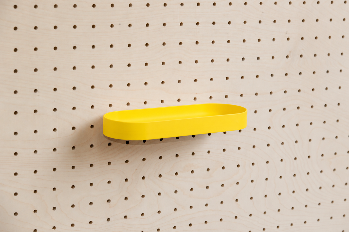 Abgerundetes Regalbrett mit Kanten in Gelb an einem Birken-Pegboard, leicht schräge Ansicht mit Schatten