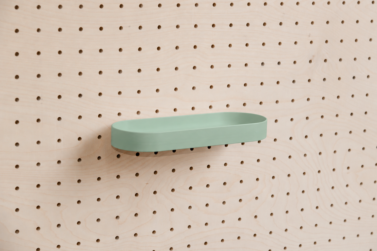 Abgerundetes Regalbrett mit Kanten in Wassergrün an einem Birken-Pegboard, leicht schräge Ansicht mit Schatten