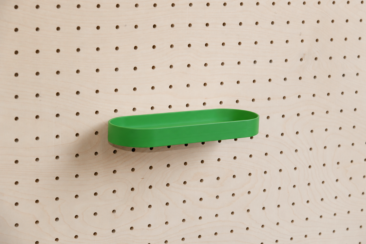 Abgerundetes Regalbrett mit Kanten in Grün an einem Birken-Pegboard, leicht schräge Ansicht mit Schatten