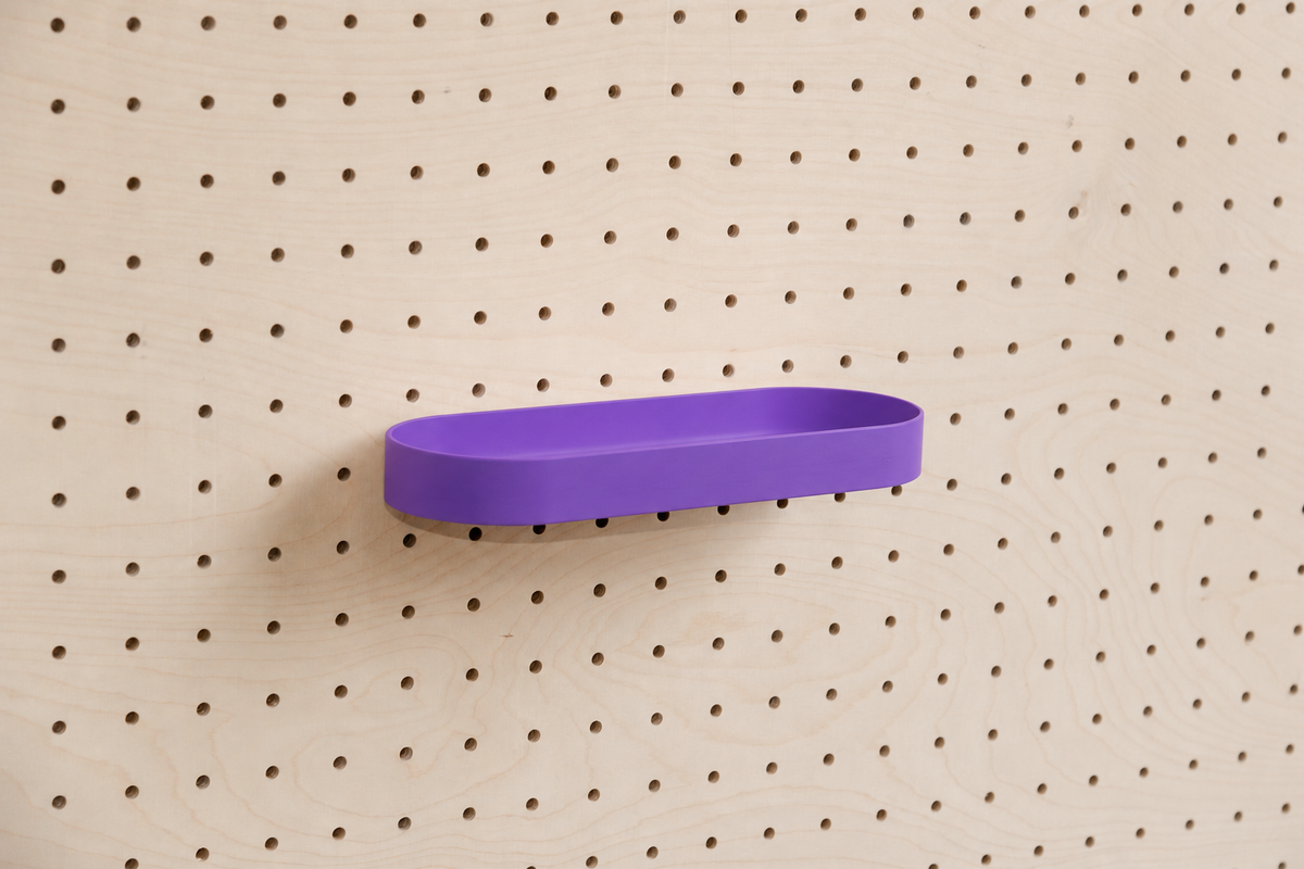 Abgerundetes Regalbrett mit Kanten in Violett an einem Birken-Pegboard, leicht schräge Ansicht mit Schatten
