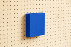 Godet porte-documents bleu pour pegboard, seul au centre d'un panneau perforé en bouleau, vue de face