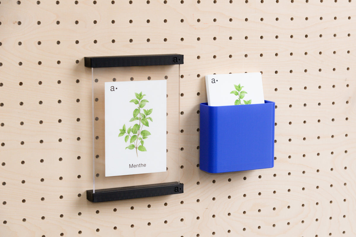 Godet porte-documents bleu et porte-affiche noir sur un pegboard en bouleau