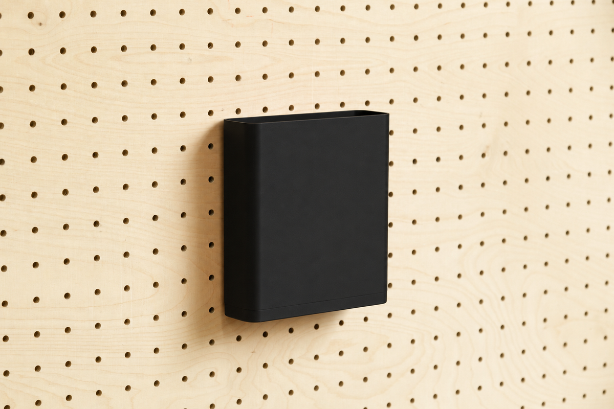 Godet porte-documents noir pour pegboard, seul au centre d'un panneau perforé en bouleau, vue de face