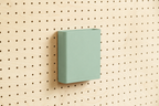 Godet porte-documents vert d'eau pour pegboard, seul au centre d'un panneau perforé en bouleau, vue de face