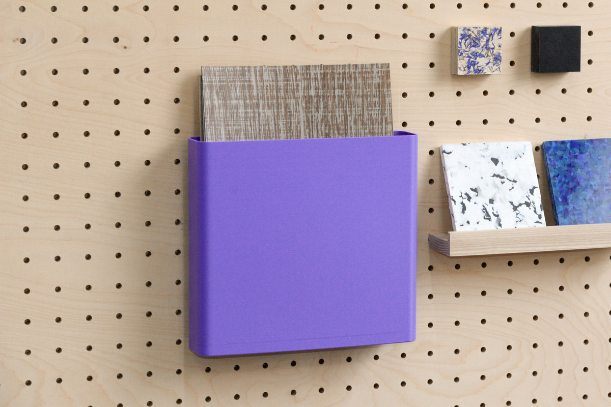 Godet violet rangeant des échantillons à côté d'une petite étagère sur un pegboard