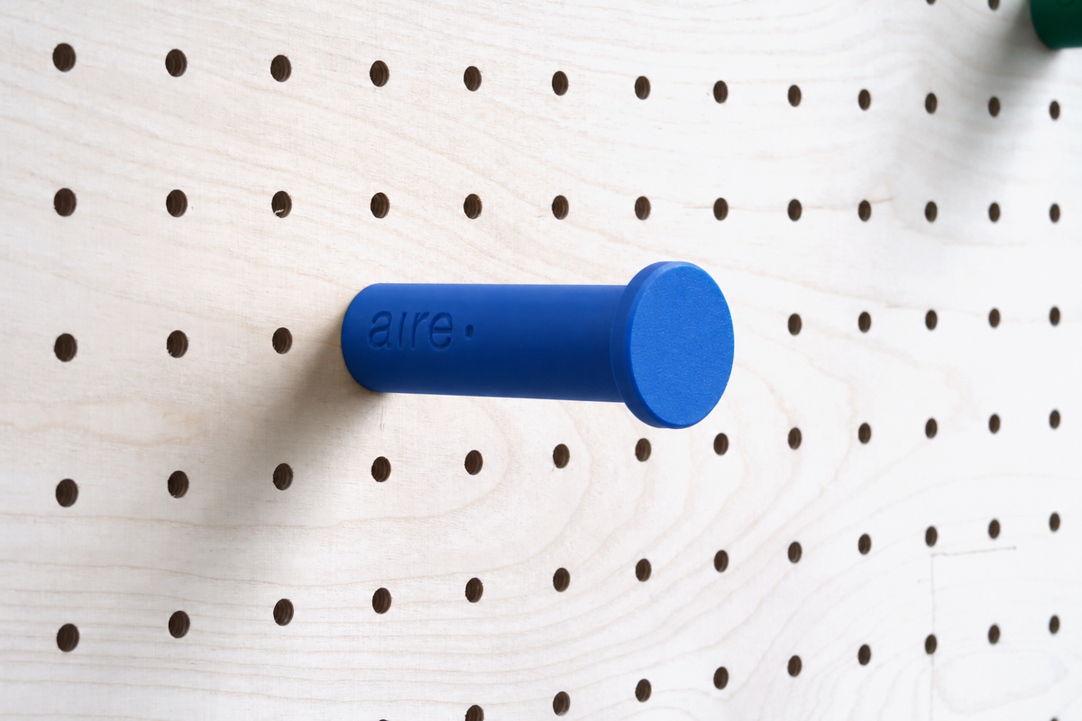 Patère colorée bleue fixée sur un pegboard en bouleau
