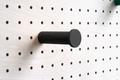 Black wall hook on a birch pegboard
