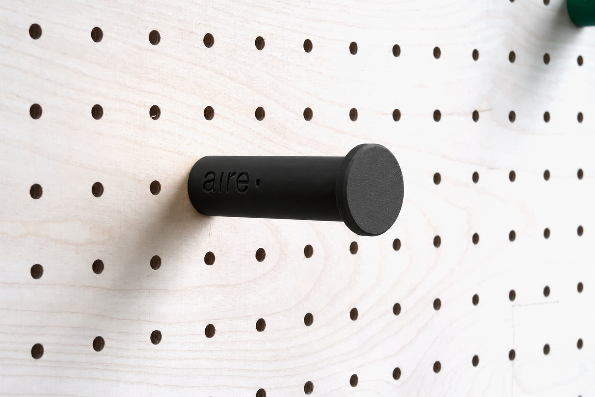 Patère colorée noire fixée sur un pegboard en bouleau