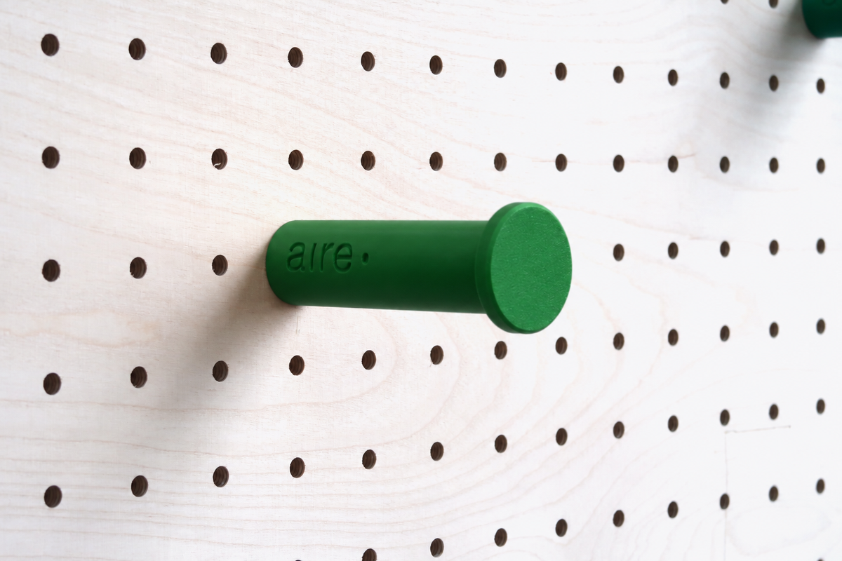 Patère colorée vert sapin fixée sur un pegboard en bouleau